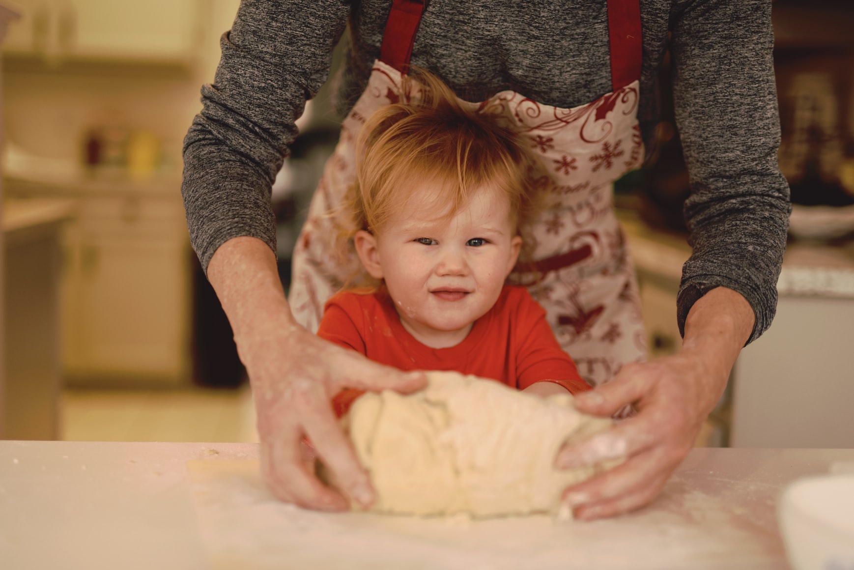 Child rolling dough with senior woman