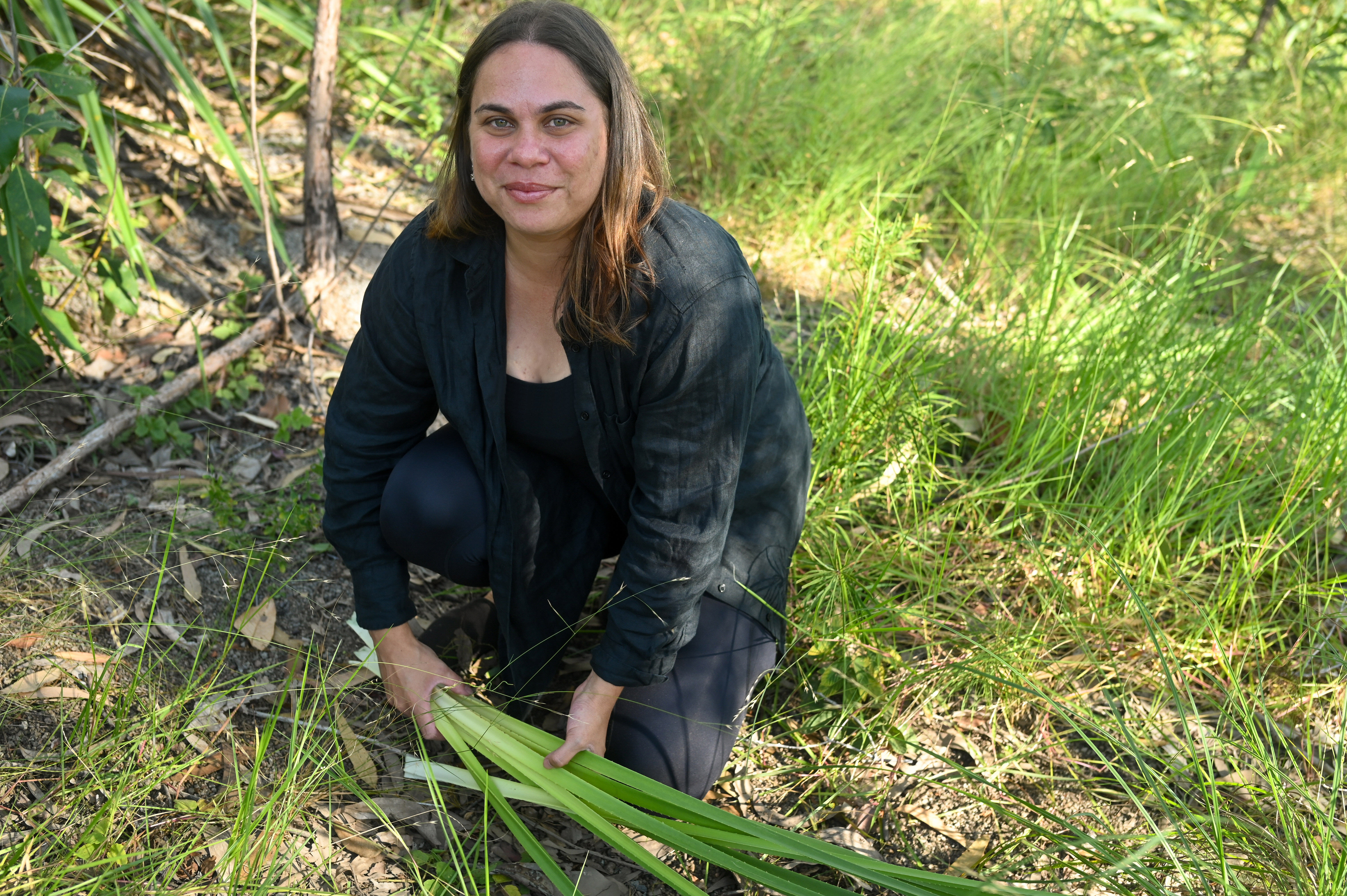 Sheridan holding pandanus leaves which have been harvested to strip and prepare for weaving.