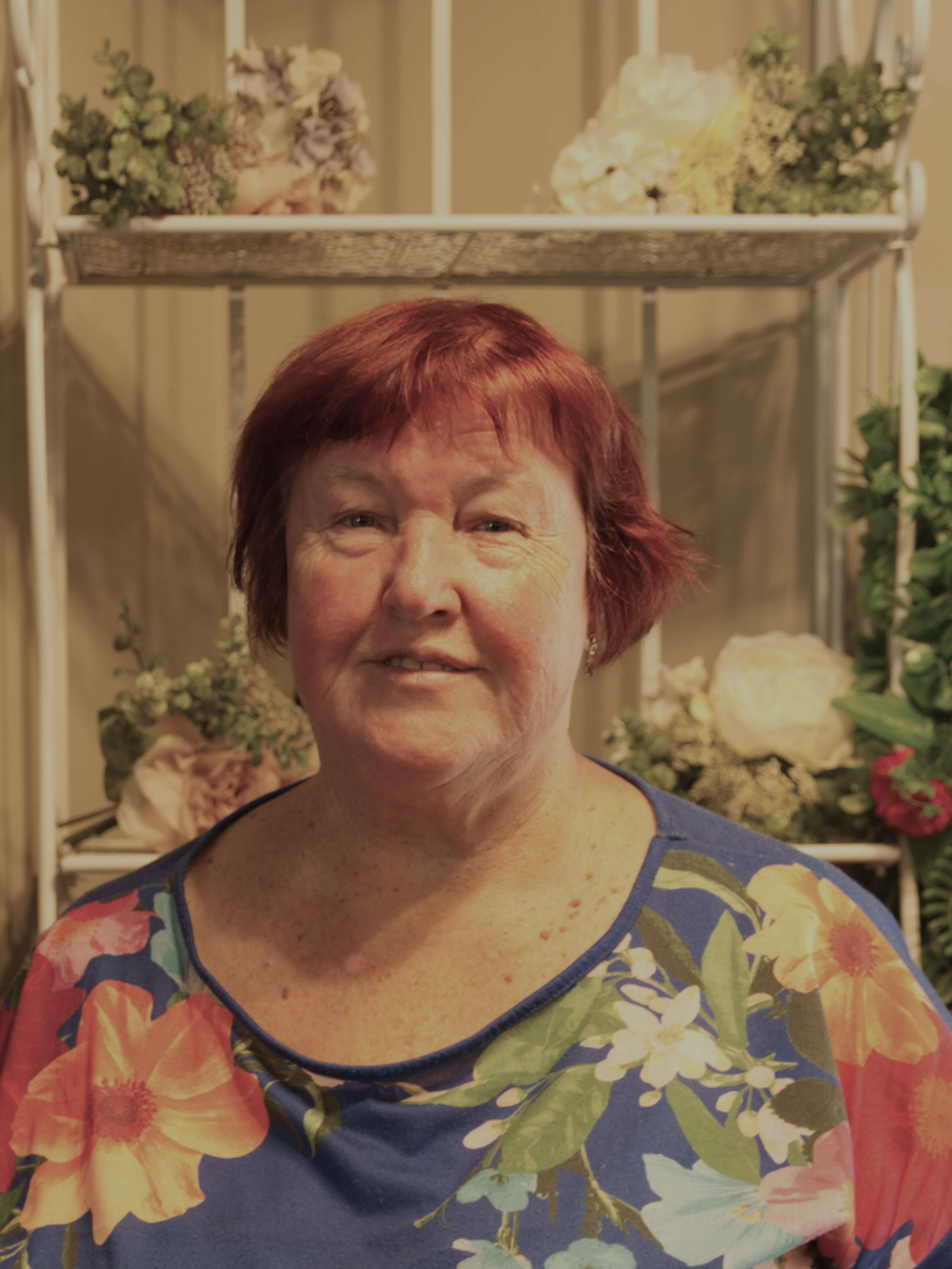 photographic portrait of Deborah Jackson, she has short red hair, and wearing a shirt with flower pattern