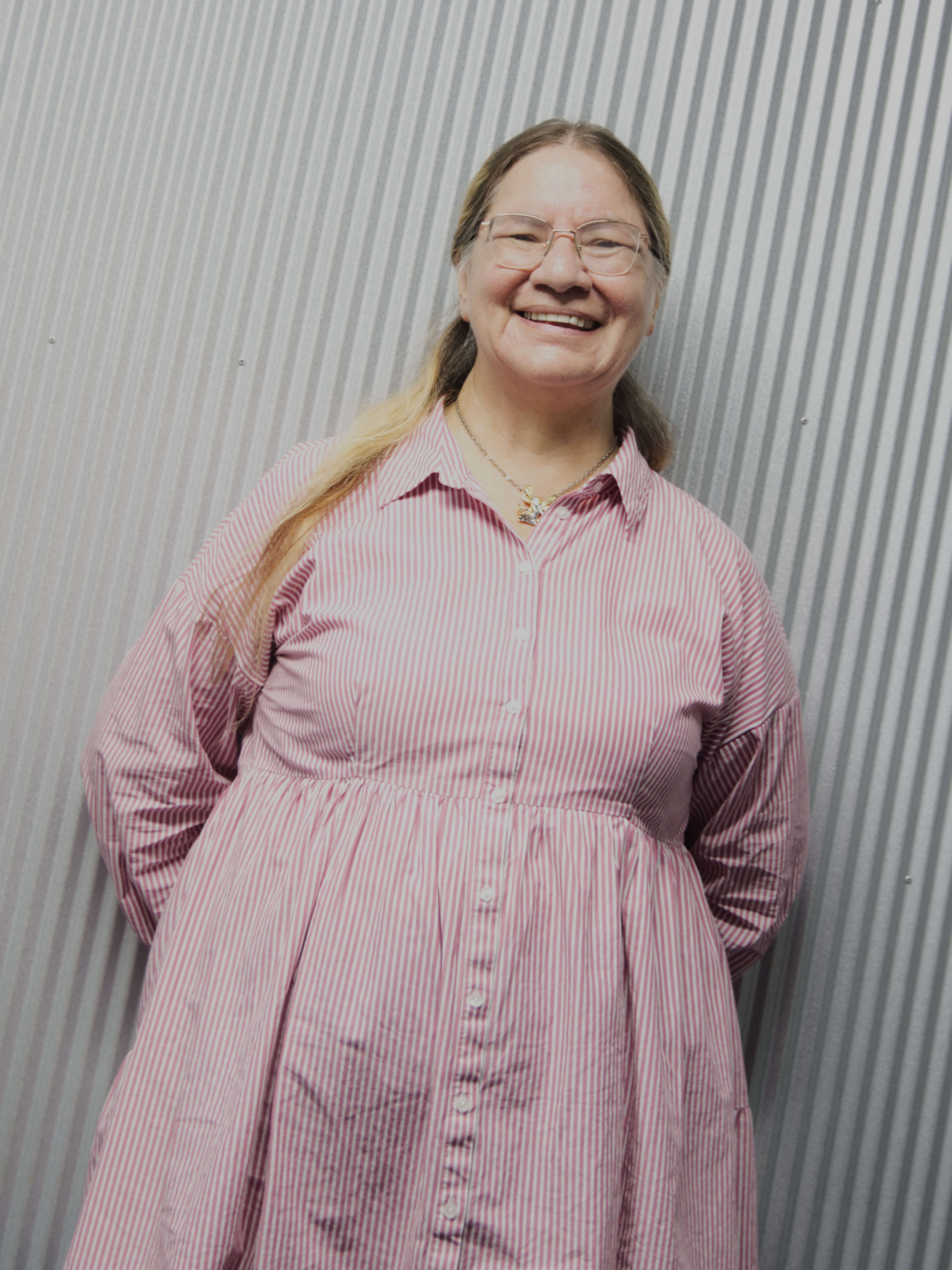 photographic portrait of a middle aged woman, Jessie Morwood, with long blonde hair, glasses, and a pink and white striped dress