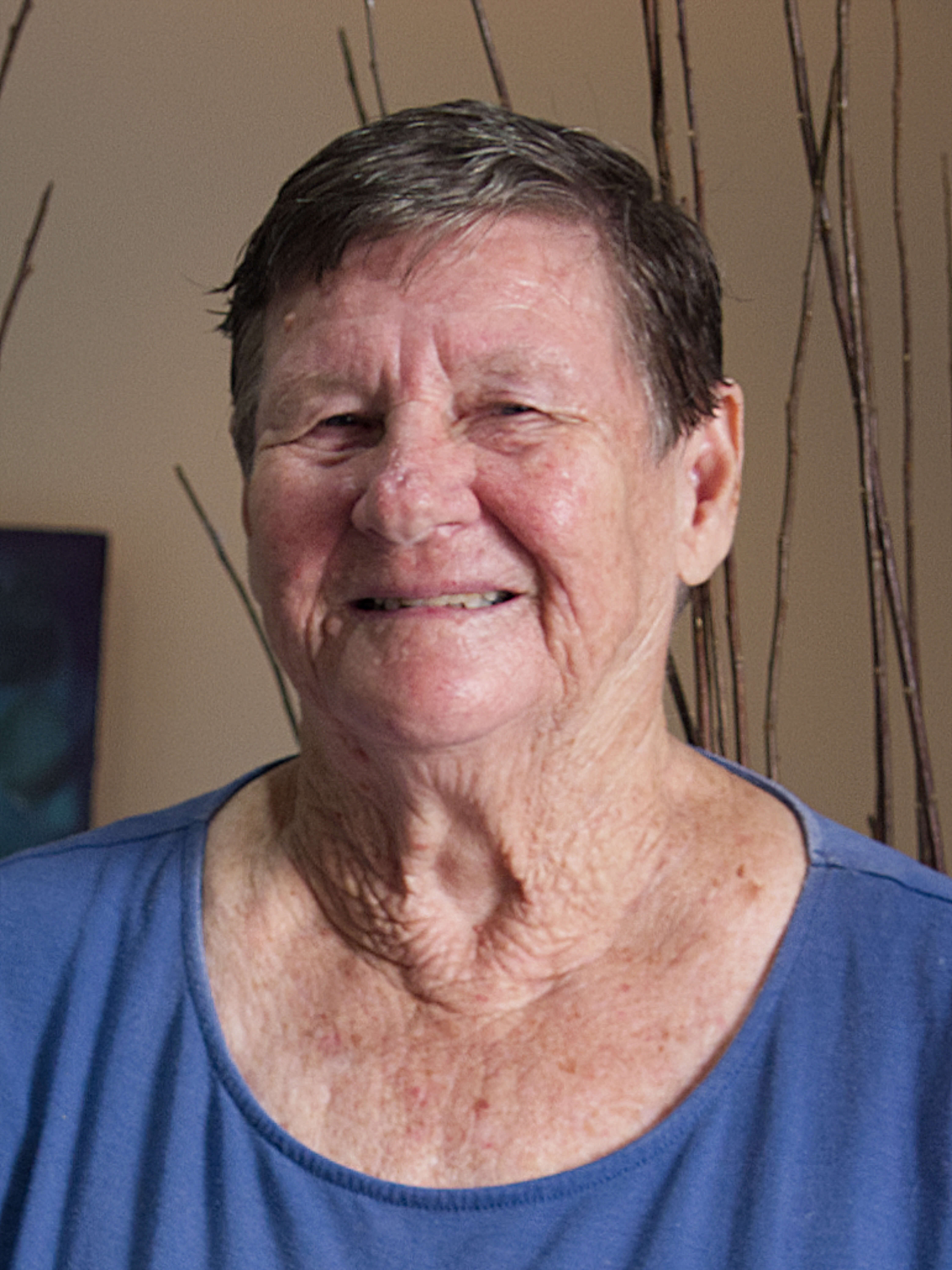 photographic portrait of Lynette Stott, she has short brown hair, a blue shirt and is smiling directly at the camera