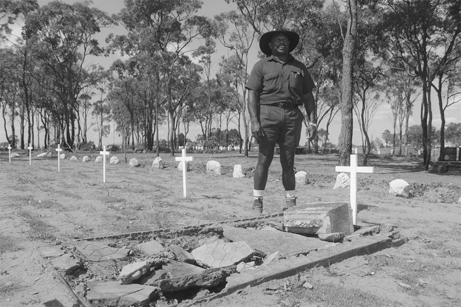 Danny Tanner standing next to an Australian South Sea Islander grave at the Bundaberg Cemetery, Queensland