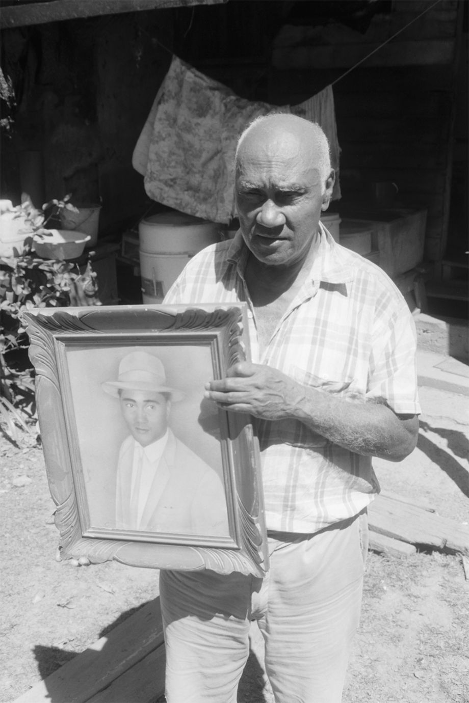 Roy Mooney holding a painting of himself when he was young in Habana, Queensland