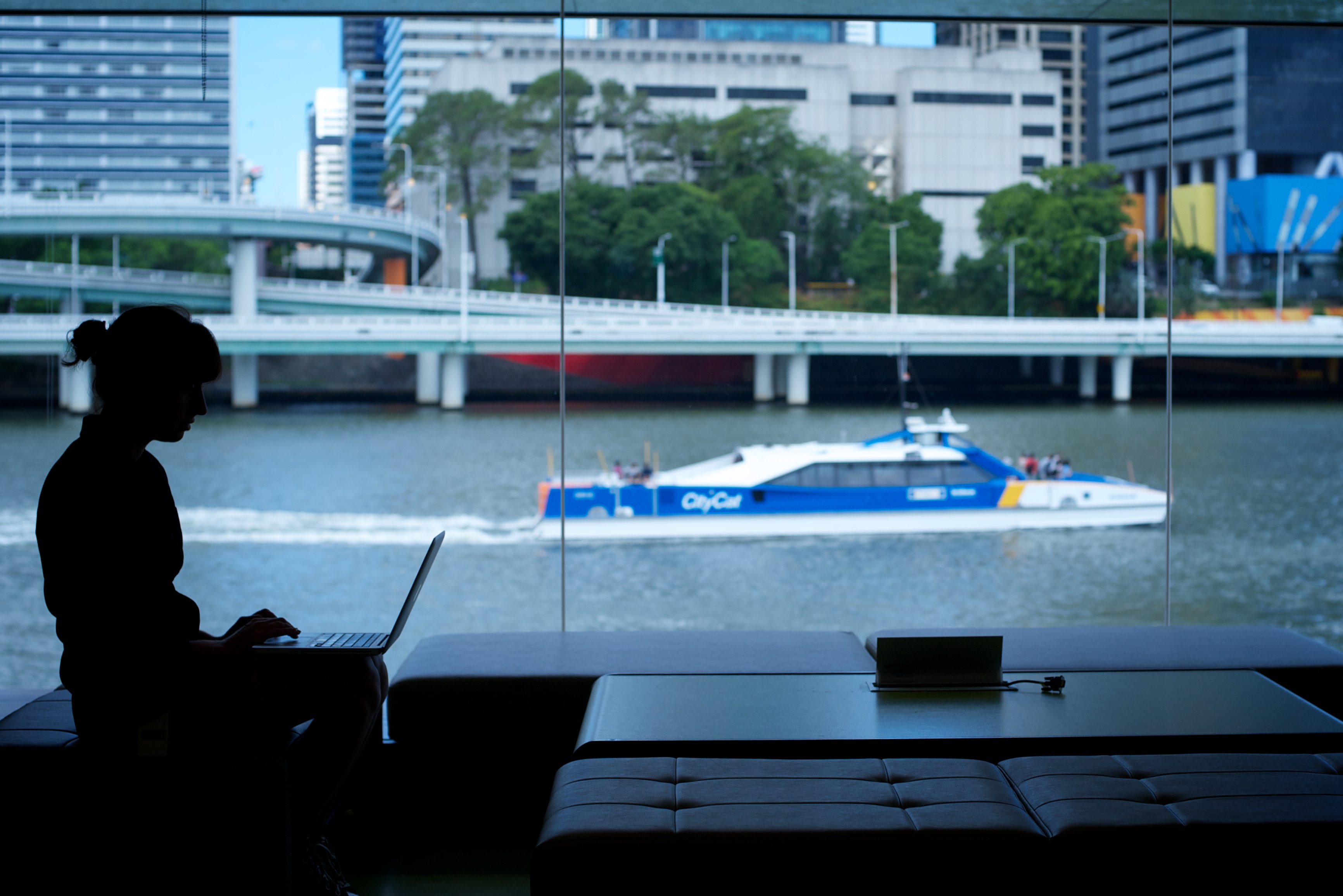 State Library at South Bank is accessible by all modes of public transport. Silhouette of a young woman with the river and City Cat ferry in the background