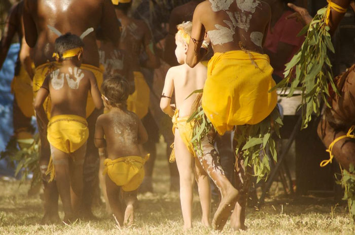 A group of small children and a few adults performing in an Aboriginal Dance Festival.