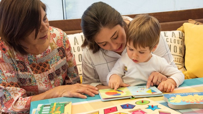 Child learning with two women through reading a book