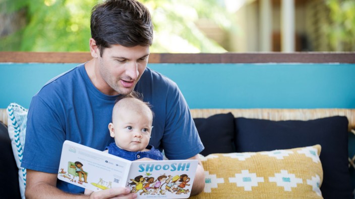 Father reading Shoosh by Simon Howe to baby