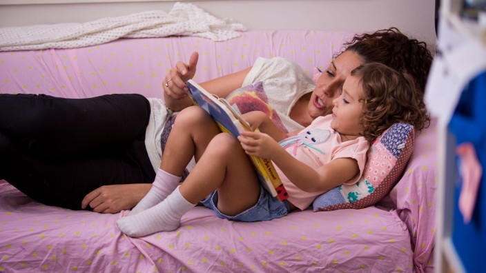 Mother and daughter reading together on couch