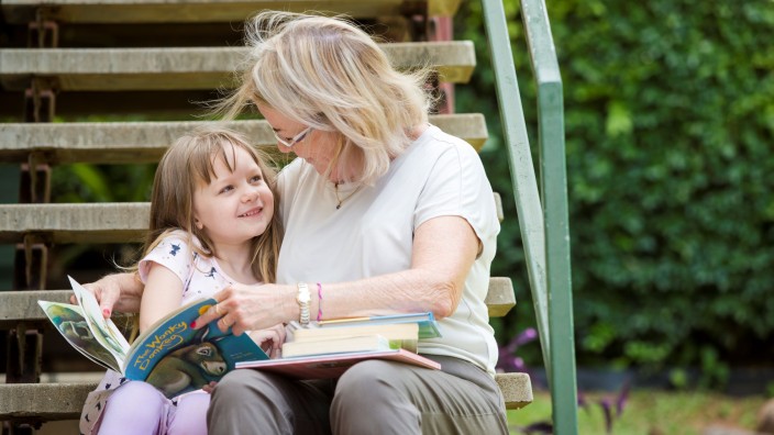 Grandmother and granddaughter reading together outside