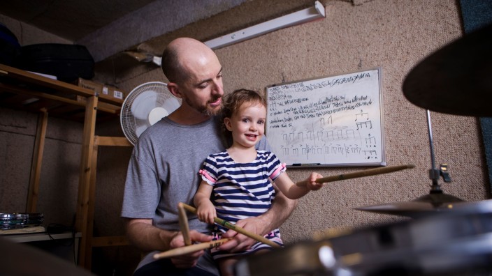Father and daughter making music together with drumkit 