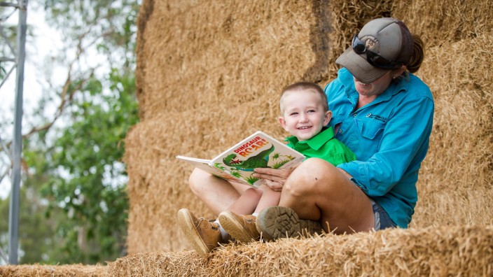 Mother and son reading book on hay bales