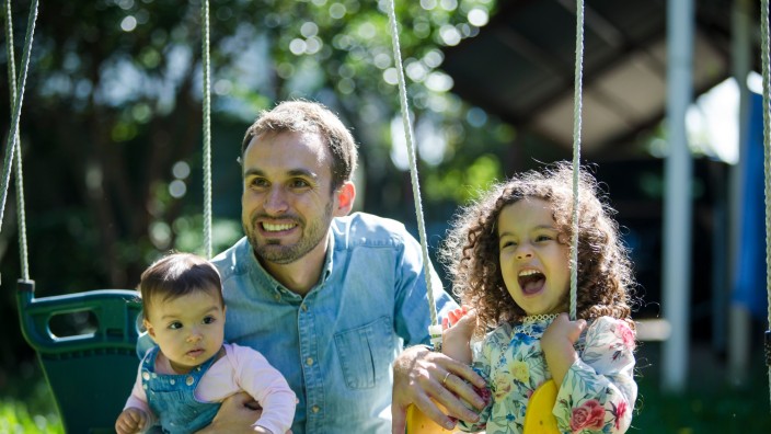 Father with two children playing on the swing 2021 photography by Jason Henry First 5 Forever image library State Library of Queensland