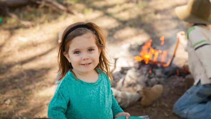 Young girl smiling with a campfire in the background