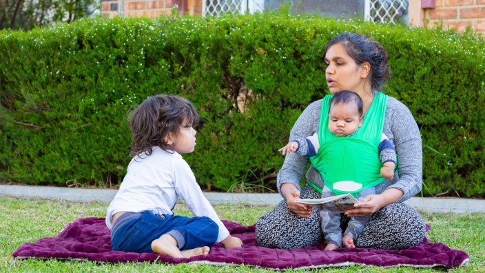 Mother and two children sharing a book outside