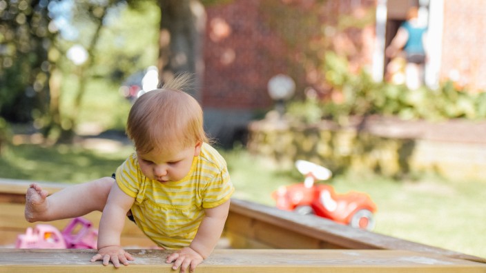 Baby climbing out of sandpit