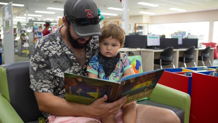 Dad and child reading a book in the library 