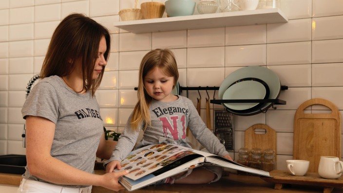 Mother and daughter looking at cookbook together