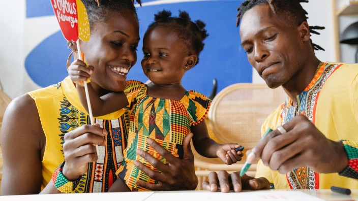 Parents and daughter celebrating Kwanzaa in traditional dress