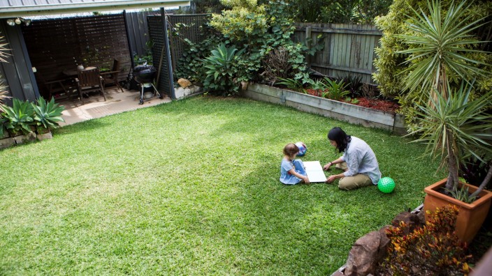 Mother and child reading a book on the grass