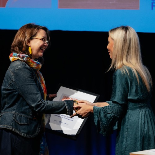 Woman accepting a framed award on stage.