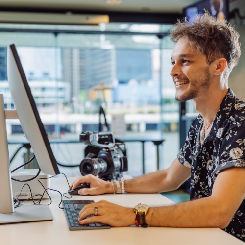 A young man working at a computer smiling