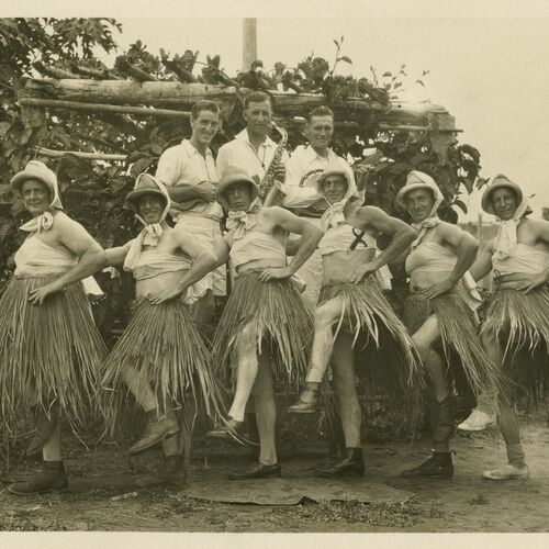 Australian men who were working gold dredging in Bulolo, Papua New Guines, entertain their fellow workers c1930s. Their skirts are made from local materials. 