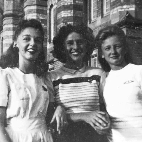 3 young women from WWII era in front of historic brick building