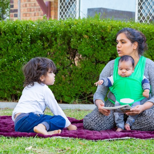 Mother and two children sharing a book outside