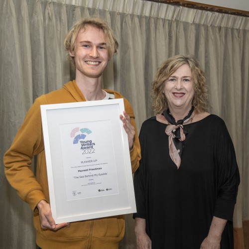 Maxwell Freedman and Vicki McDonald smiling; Maxwell is holding a framed certificate