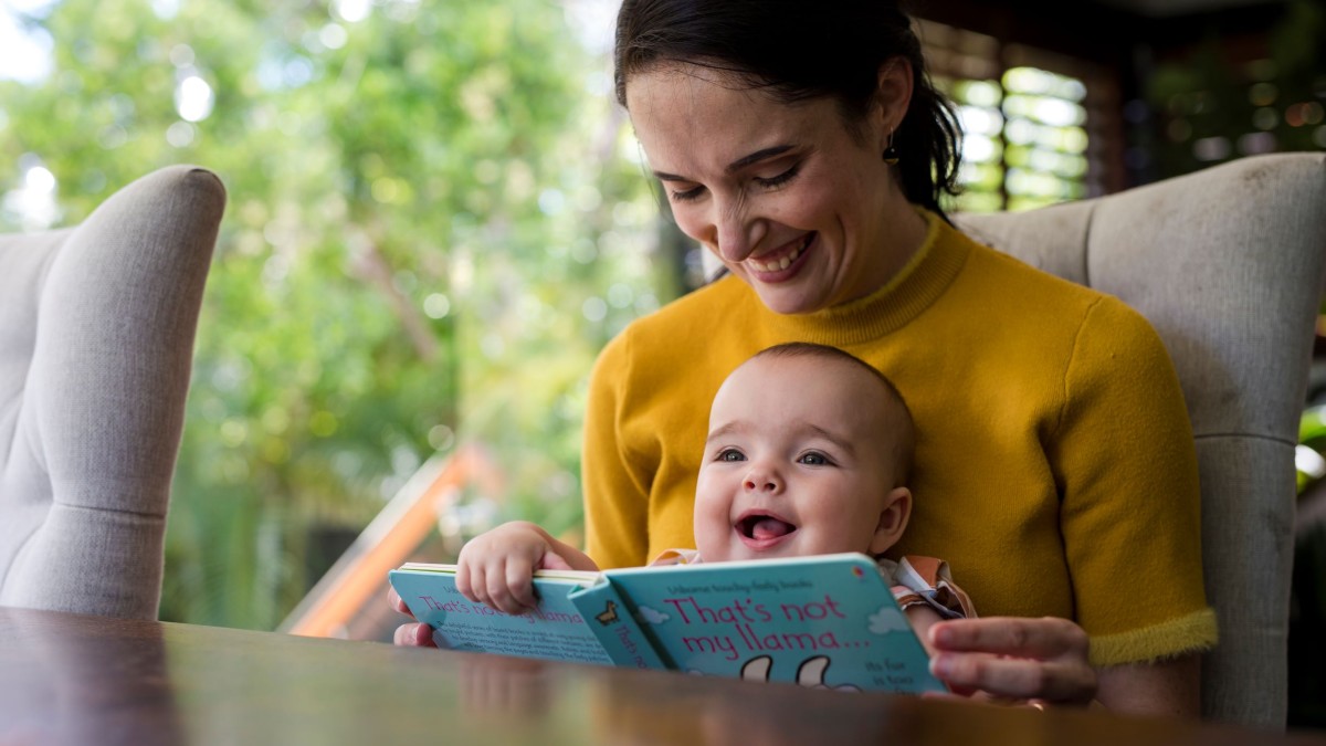 Mother and baby reading a board book inside