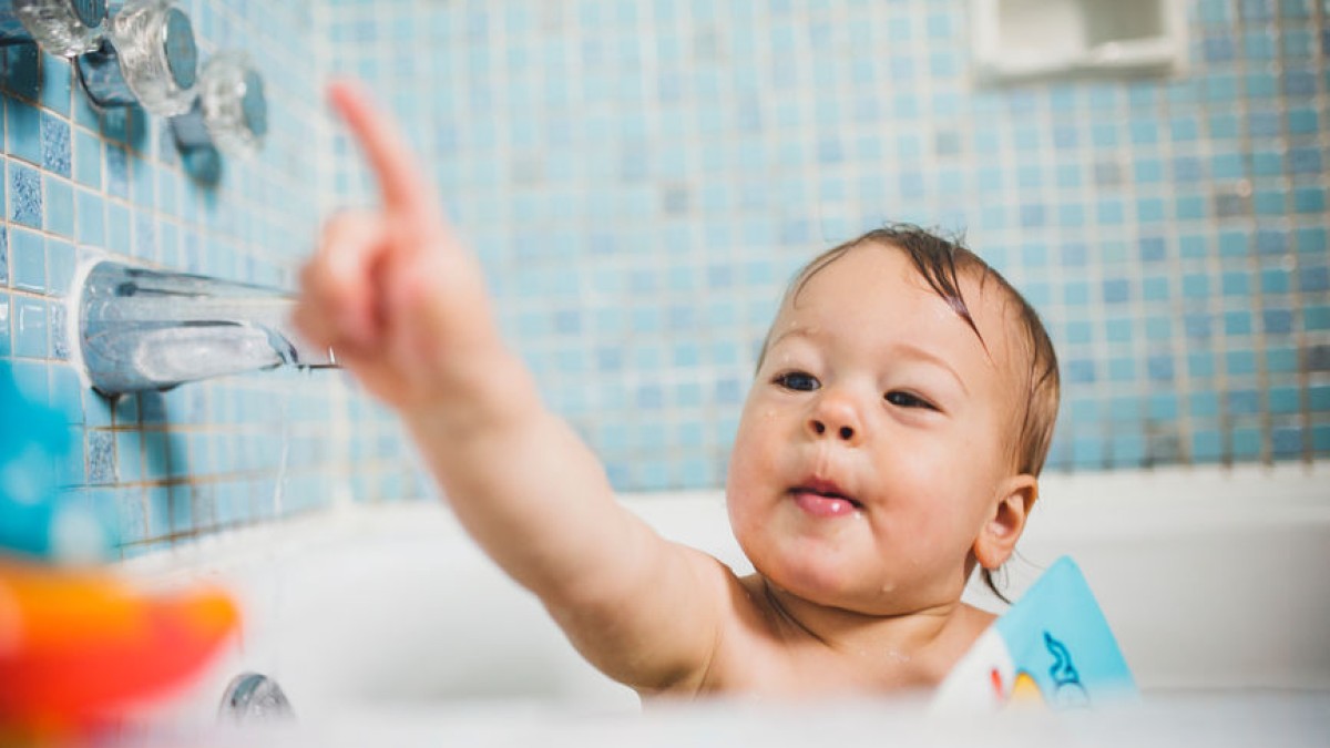 Baby in bath pointing finger