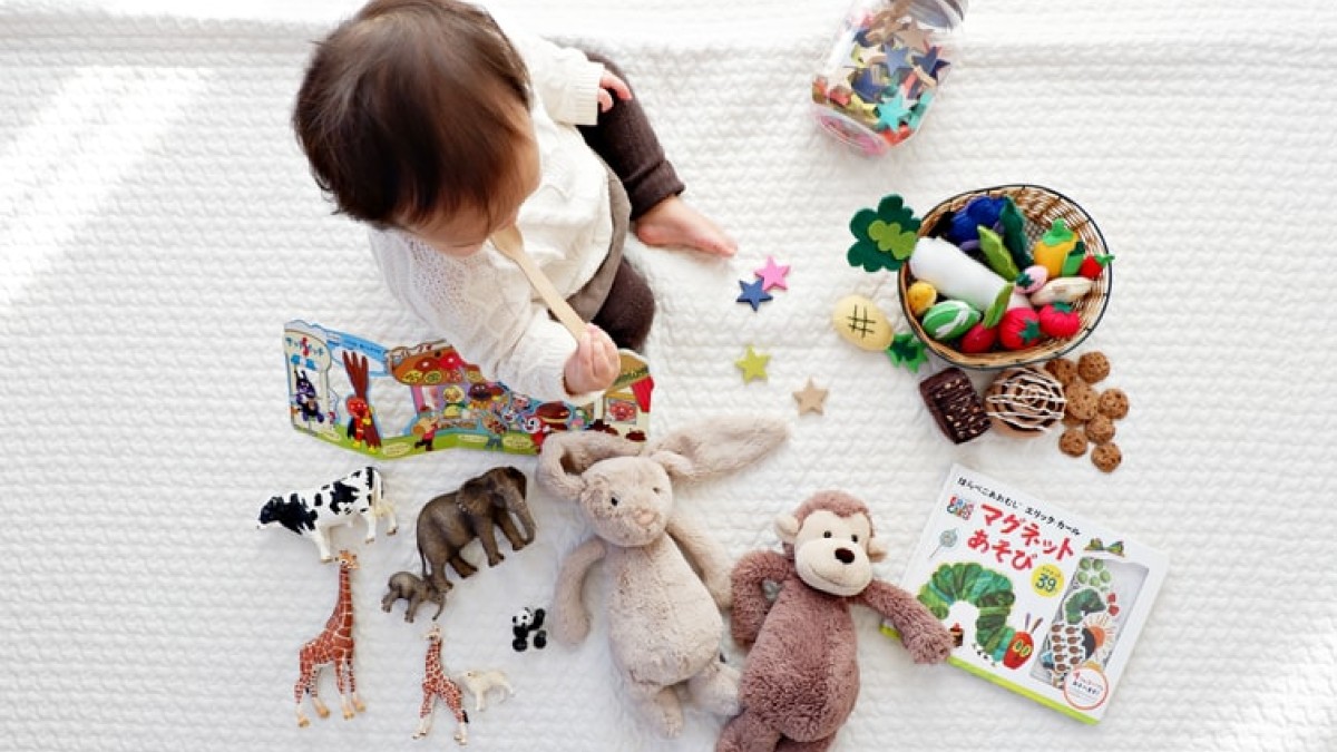 A baby sits with toys and books 