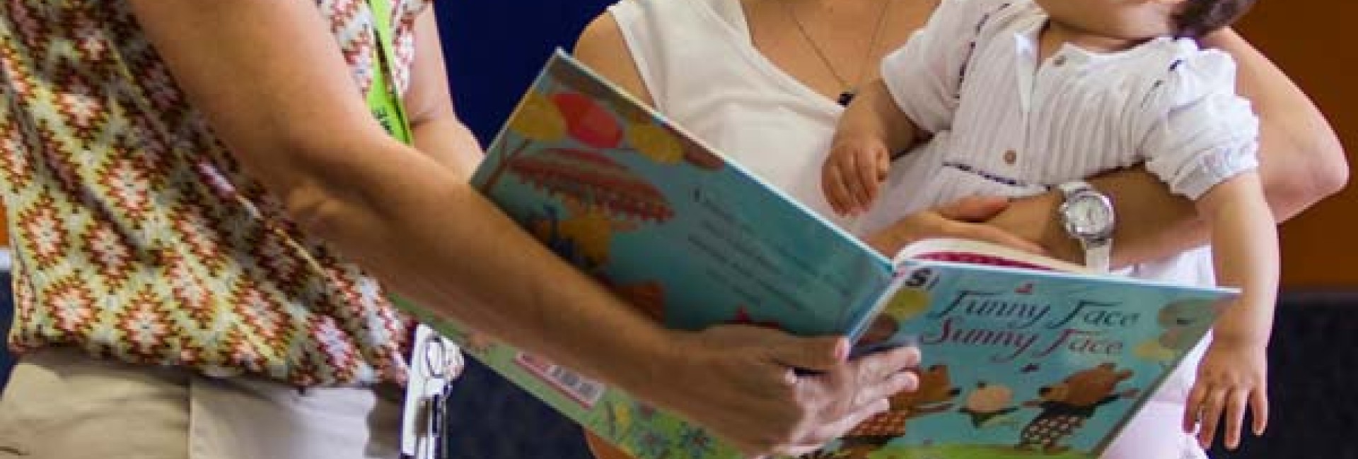 Woman and baby reading book with librarian
