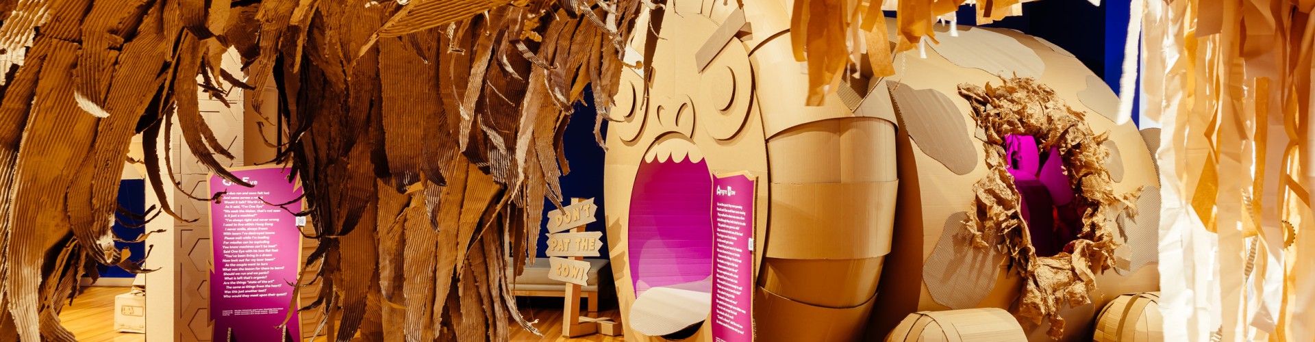 A large cardboard leg from an imaginary beast in the foreground with a cardboard cow in the background who has a very animated face