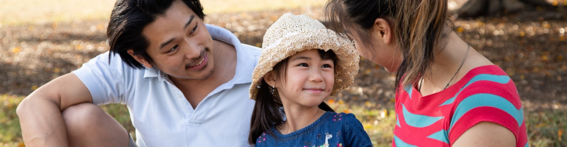 Father and mother reading book with daughter in park
