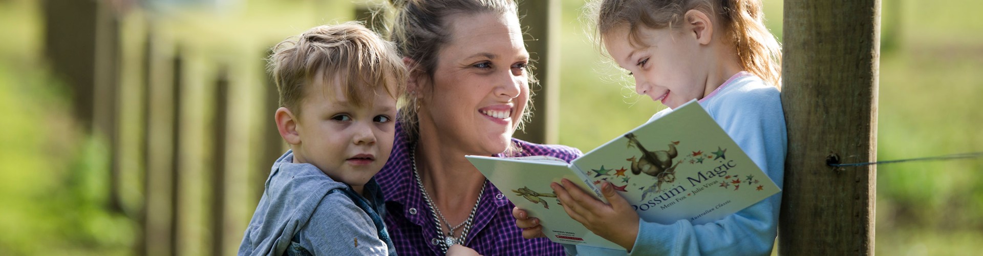 Mother and children on farm reading a book
