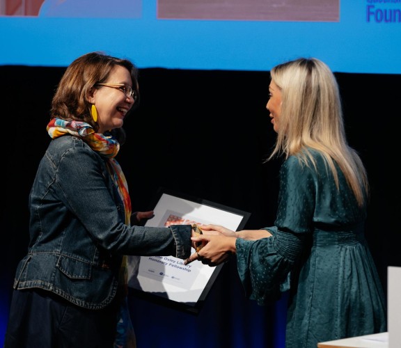 Woman accepting a framed award on stage.