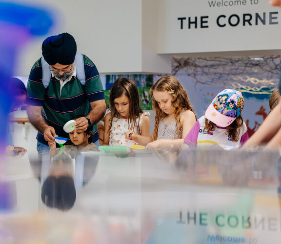 Children and families doing arts and crafts at Holiday Fun event, State Library of Queensland