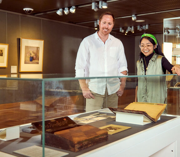 Two people looking at items in a glass case.