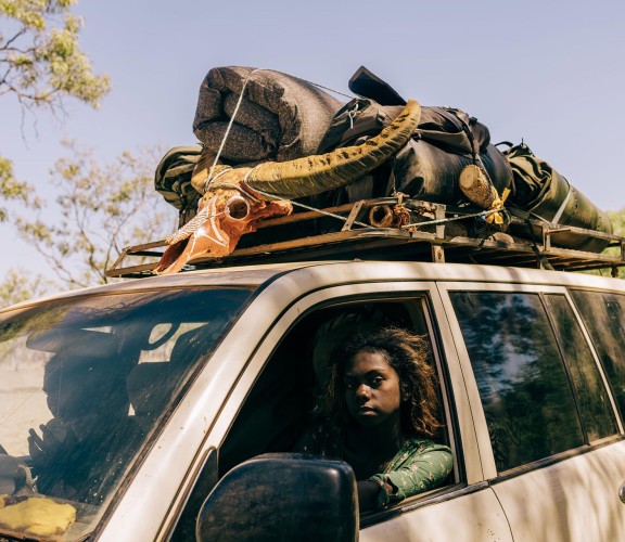 Two people in a car with items stored on the foor.