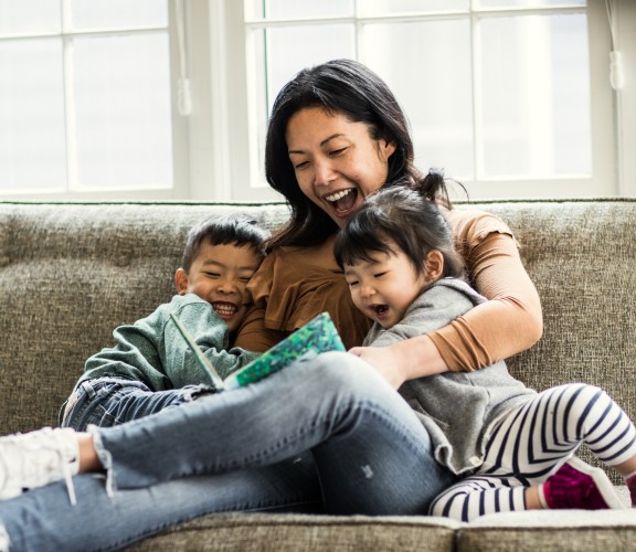 Mother with son and daughter reading on a couch