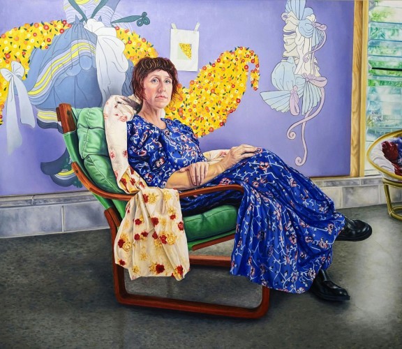 Portrait of woman in a dress sitting in a colourful room.