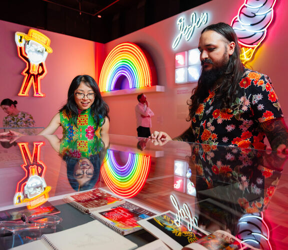 Two visitors viewing neon signs inside slq Gallery