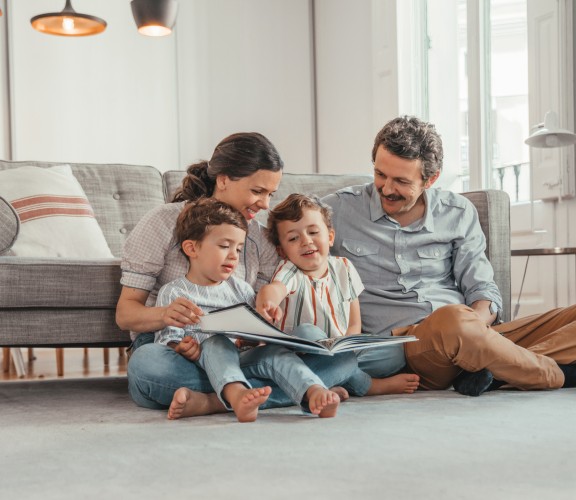 Family reading a book on the floor in living room