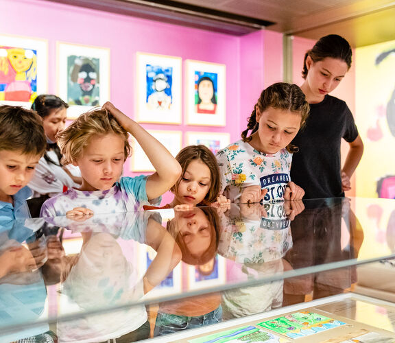 Group of kids looking at children's paintings.