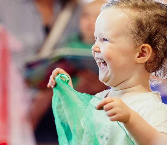 Happy child playing with a piece of fabric