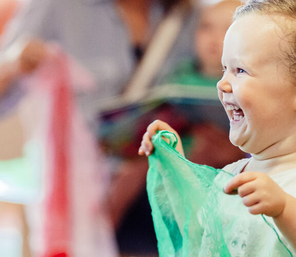 Happy child playing with a piece of fabric