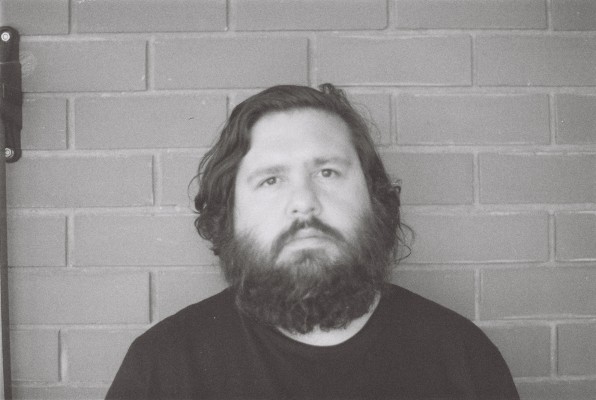 Black and white photo of Dominic Guerrera standing against a brick wall