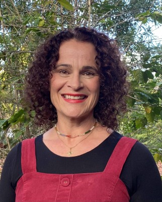 Headshot of Nicky Peelgrane who wears black and red and smiles in a garden