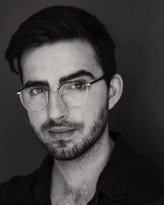 Black and white photo of Jonathan O'Brien. He wears glasses and a dark shirt.